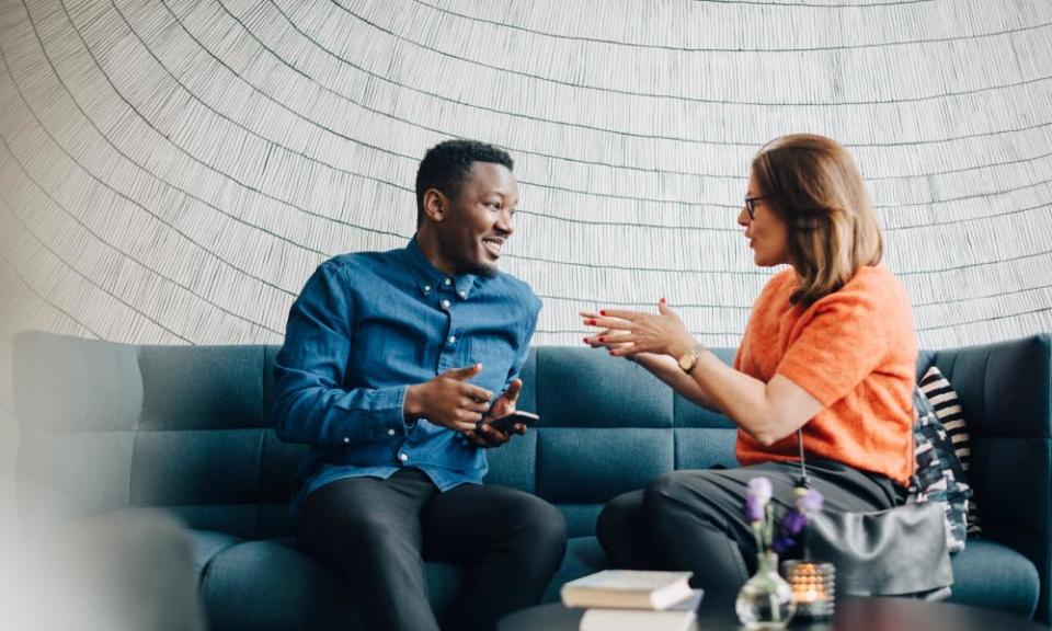 Businessman and woman using mobile phones while sitting on couch during conference