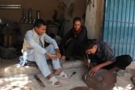 Unemployed Afghan Saber Rezayee (R) chats with his friends as he helps out at his family's heater shop in Mazar-i-Sharif on September 20, 2013