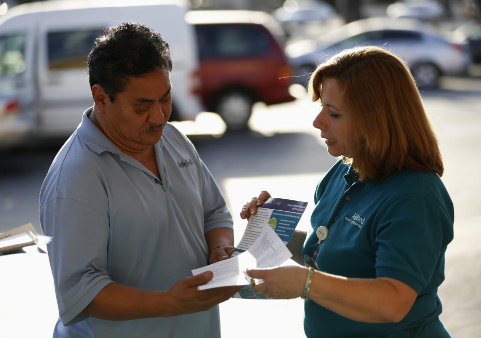 Engrith Acosta, patient care coordinator at AltaMed, speaks to a man during a community outreach on Obamacare in Los Angeles, California November 6, 2013. Concerns among Hispanics that signing up for medical insurance under President Barack Obama's healthcare law may draw the scrutiny of immigration authorities has hurt enrollment, according to advocates of the policy. To match Feature USA-HEALTHCARE/HISPANICS  Picture taken November 6, 2013. REUTERS/Mario Anzuoni  (UNITED STATES - Tags: POLITICS HEALTH)