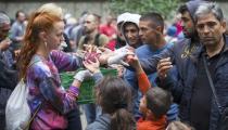 A helper distributes fruit to migrants in front of the State Office for Health and Social Affairs (LaGeSo), in Berlin, Germany, September 3, 2015. REUTERS/Hannibal Hanschke