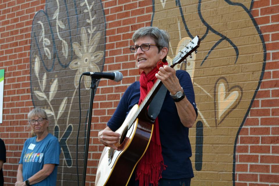 Columbia/Boone County Public Health and Human Services Health Educator Heather Harlan sings an original song Wednesday at the dedication of the 'Kindness Heals' mural on the building the department shares with Compass Health.