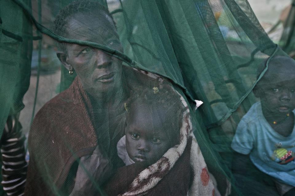 FILE - In this Thursday, Jan. 2, 2014 file photo, one of the few to have a mosquito net, a displaced family who fled the recent fighting between government and rebel forces in Bor by boat across the White Nile, sit under it after waking up in the morning in the town of Awerial, South Sudan. The U.N.'s top official for human rights Navi Pillay told a news conference in South Sudan's capital Juba on Wednesday, April 30, 2014 that the country is on the verge of catastrophe because of a deadly mix of recrimination, hate speech and revenge killings since December and that she is appalled by the apparent lack of concern by leaders in South Sudan over the risk of a potential famine. (AP Photo/Ben Curtis, File)