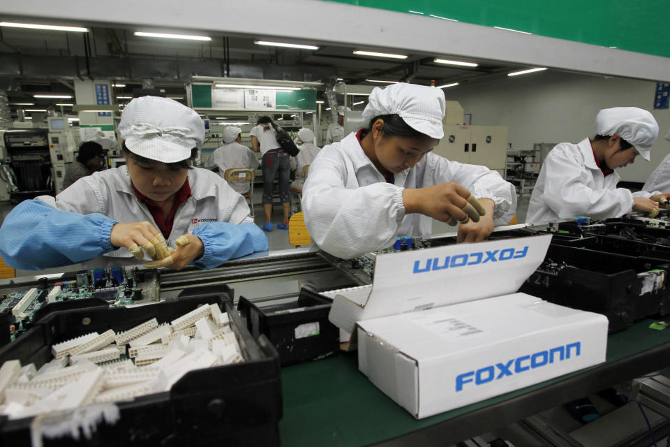 FILE - In this May 26, 2010 file photo, staff members work on the production line at the Foxconn complex in the southern Chinese city of Shenzhen, southern China. Wisconsin Gov. Scott Walker says President Donald Trump plans to make a "major jobs announcement for Wisconsin" as anticipation builds it will be about electronics giant Foxconn locating in the state. Taiwan-based Foxconn is best known as the assembler of the iPhone. Wisconsin is among seven states, mostly in the Midwest, that the company has named as possible locations to build the its first liquid-crystal display factory that could mean tens of thousands of jobs. (AP Photo/Kin Cheung, File)