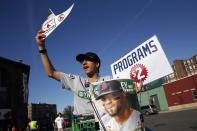 FILE - In this May 18, 2019, file photo, a vendor sells programs outside Fenway Park before a baseball game between the Boston Red Sox and the Houston Astros in Boston. There will be empty ballparks on what was supposed to be Major League Baseball's opening day. There will be no vendors in the stands selling peanuts and Cracker Jack for baseball fans ready to come back. The start of the MLB regular season is indefinitely on hold because of the coronavirus pandemic. (AP Photo/Michael Dwyer, File)