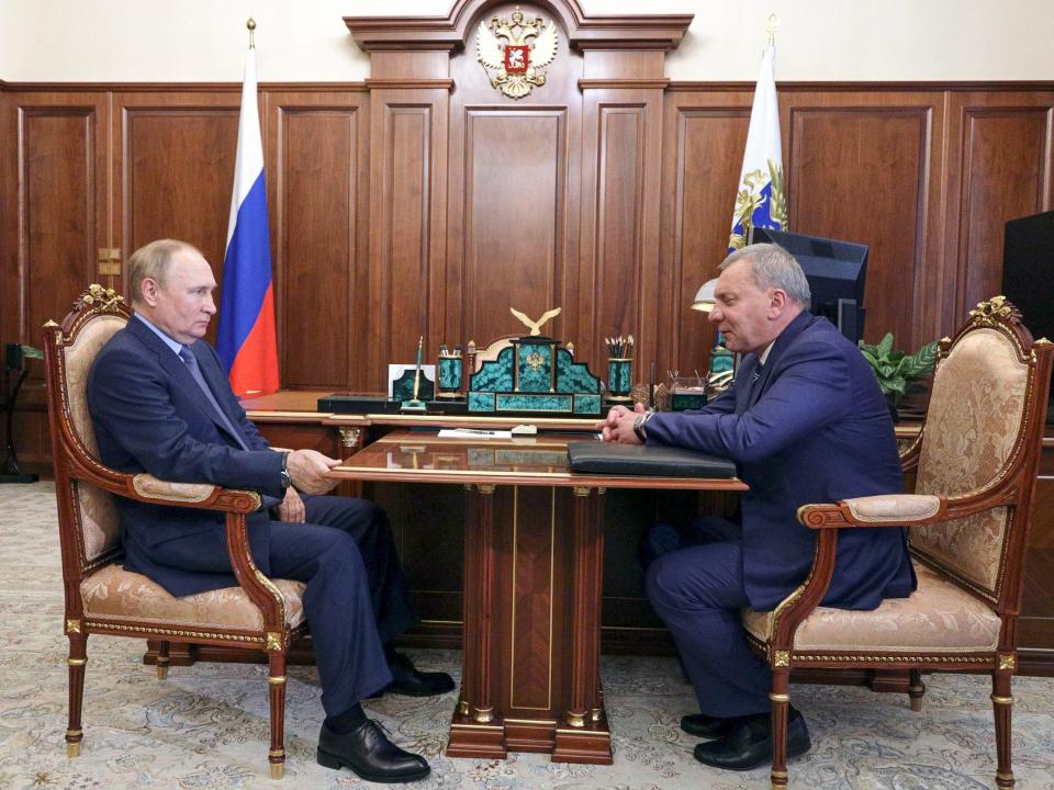 vladimir puting and yuri borisov wearing suits sit at table in office room with wood panels