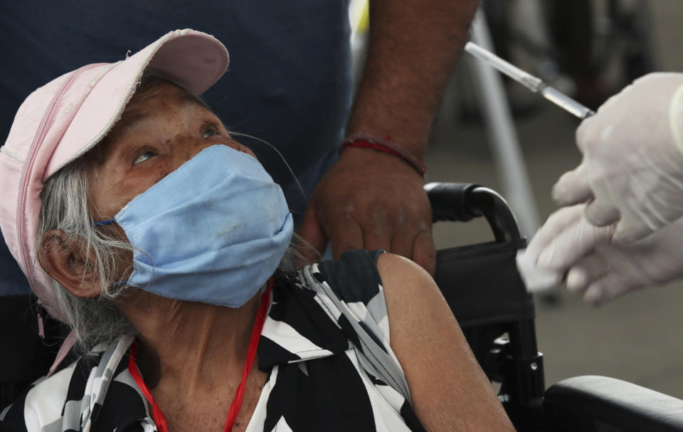 An elderly woman looks at a health worker before getting her shot of the Sinovac Biotech COVID-19 vaccine at the Americas sports center in Ecatepec, a borough on the outskirts of Mexico City, Tuesday, Feb. 23, 2021. (Foto AP/Marco Ugarte)