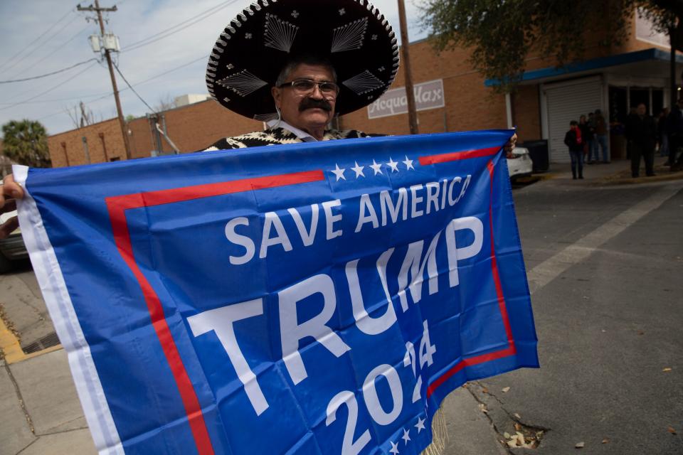 A Donald Trump supporter in Eagle Pass holds up a banner.
