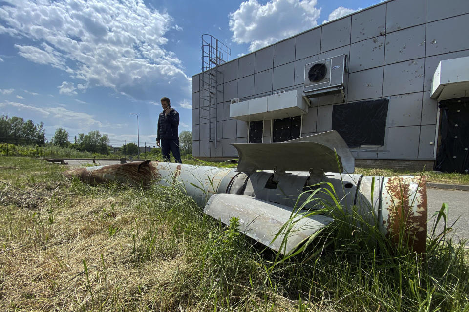 Andrii Savchenko, head of the department for ensuring the operation of engineering of the National Scientific Center "Kharkov Institute of Physics and Technology" speaks by phone in front of a fragment of a Russian rocket which hit territory of the institute in Kharkiv, Ukraine, Thursday, May 18, 2023. More than a year after missiles first hit, the wind batters boarded-up windows and exposed insulation flaps in the wind. Debris has been heaped in piles, and rocket parts sit near craters up to 2.5 meters (8 feet) deep. (AP Photo/Oleksandr Brynza)