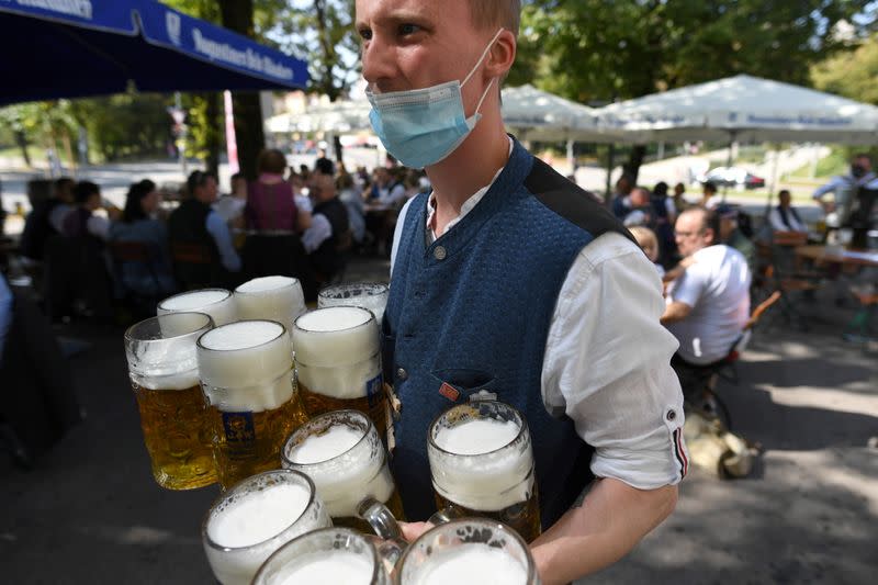 FILE PHOTO: Server carries mugs during the tapping of a barrel at a beer garden near Theresienwiese