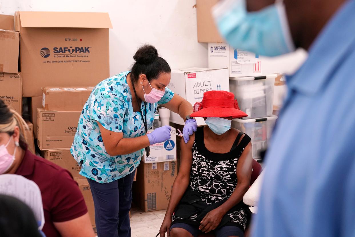 La enfermera registrada Ashleigh Velasco, a la izquierda, administra la vacuna Johnson & Johnson COVID-19 a Rosemene Lordeus, a la derecha, en una clínica de Healthcare Network en Immokalee, Fla. (AP)