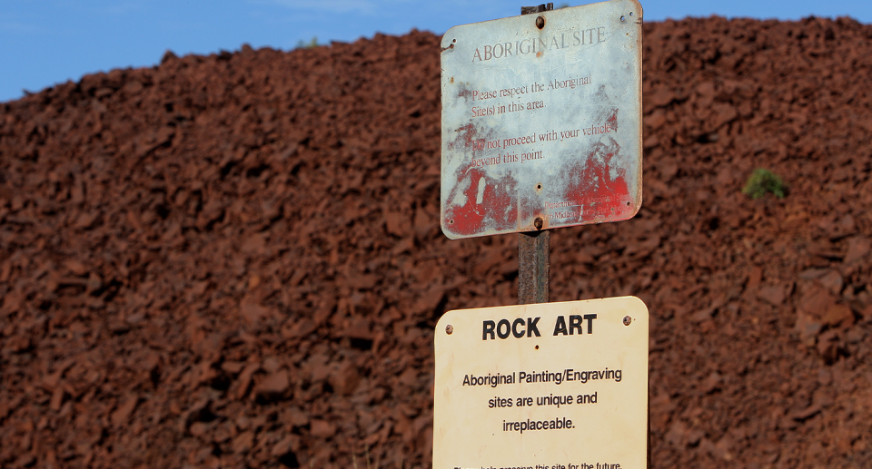 A rock art sign in front of a pile of rock art at the Burrup Peninsula