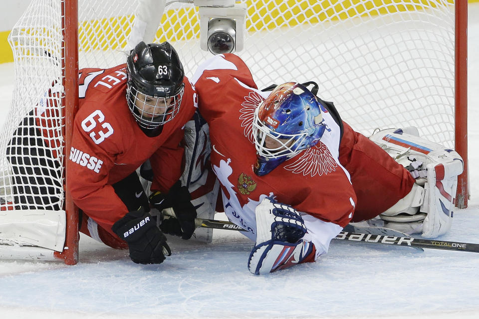 Anja Stiefel of Switzerland and Goalkeeper Anna Prugova of Russia slide into the net during the 2014 Winter Olympics women's ice hockey quarterfinal game at Shayba Arena, Saturday, Feb. 15, 2014, in Sochi, Russia. (AP Photo/Matt Slocum)