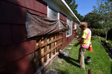 Mike McCorkle shows where he has exposed woodwork on the outside of his house to dry following flooding brought by Hurricane Harvey late last month in Bellaire, Texas, U.S., September 8, 2017. REUTERS/Nick Carey