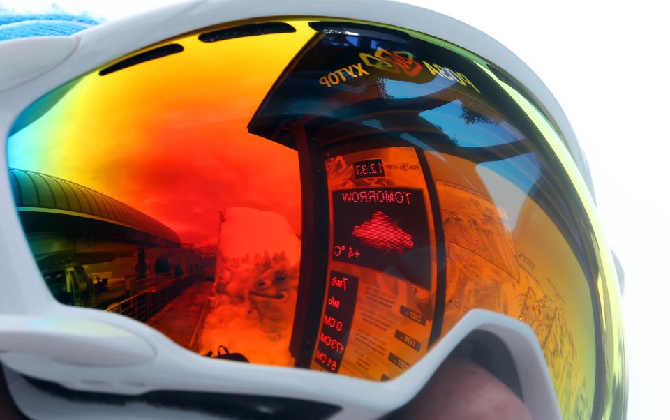 The forecast for tomorrow's temperature is reflected in the ski goggles of a volunteer at the Sochi 2014 Winter Olympics, Tuesday, Feb. 11, 2014, in Krasnaya Polyana, Russia. Warm temperatures in the mountains made the snow too soft and caused the cancellation of Women's downhill training on Tuesday. (AP Photo/Luca Bruno)