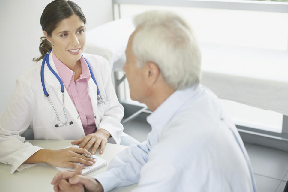 A female doctor sitting at a table talking to a male patient
