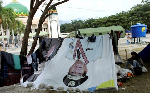 A tent is made with a banner of Central Sulawesi Governor Longki Djanggola at a camp for displaced victims  - Credit: JORGE SILVA/REUTERS