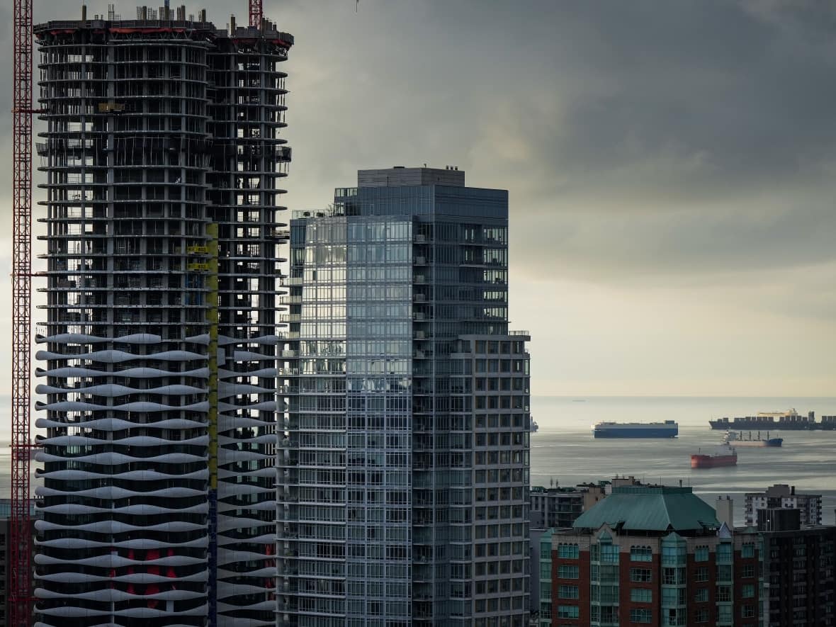 A condo tower is seen under construction in downtown Vancouver as freighters sit at anchor on English Bay. Critics panned the budget's relative inaction on housing. (Darryl Dyck/Canadian Press - image credit)