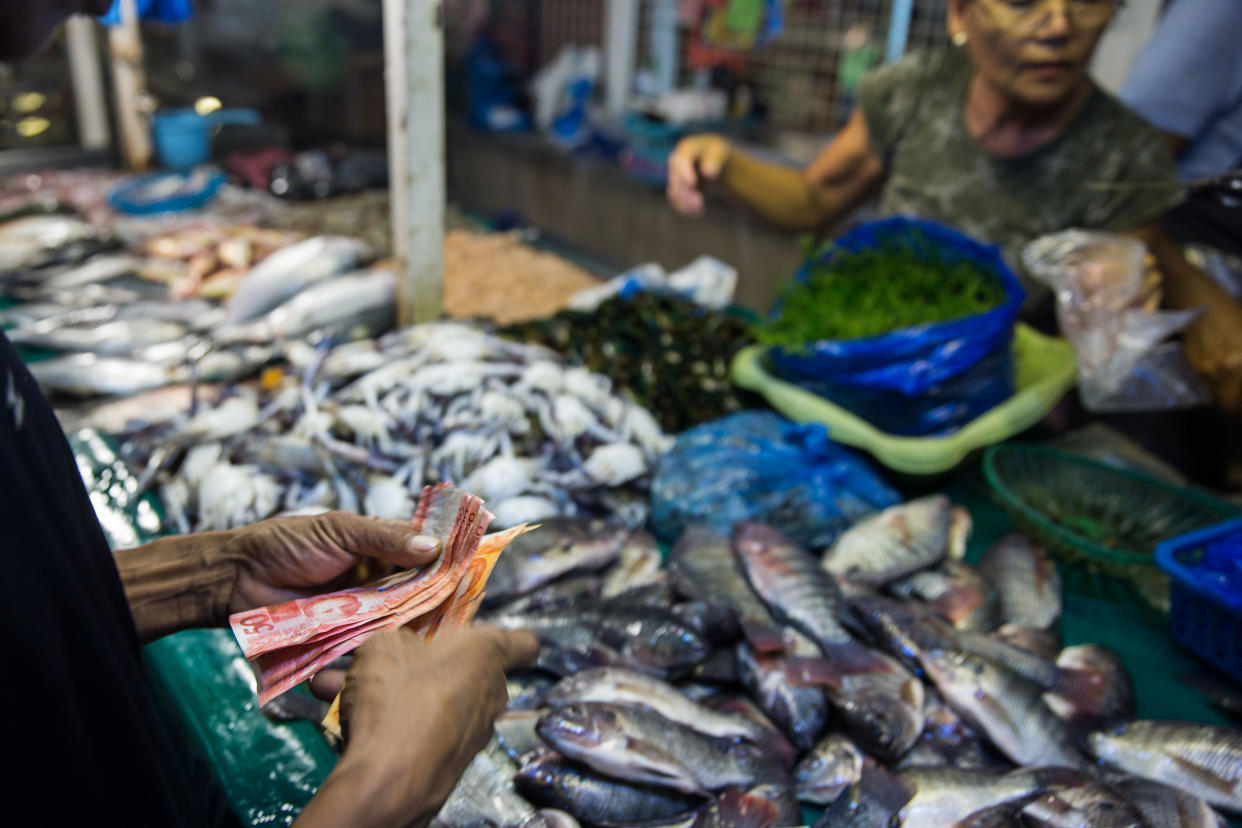 A man counts Philippine peso banknotes at a stall selling fish at Quiapo Market in Manila, the Philippines. (Photo: Getty Images)