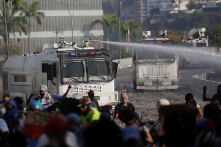 Demonstrators react in front of a burning military vehicle during clashes with security forces following a rally against the government of Venezuela's President Nicolas Maduro and to commemorate May Day in Caracas, Venezuela May 1, 2019. REUTERS/Ueslei Marcelino