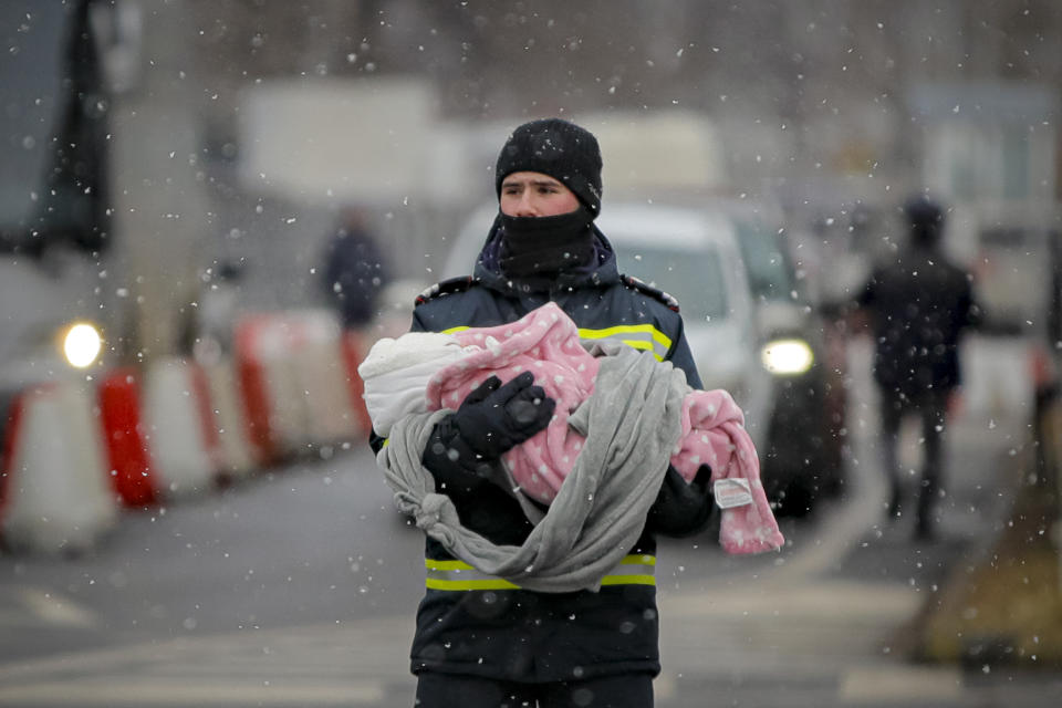 FILE - A firefighter holds the baby of a refugee fleeing the conflict from neighboring Ukraine at the Romanian-Ukrainian border, in Siret, Romania, Monday, March 7, 2022. Since Russia launched its attacks against Ukraine on Feb. 24, more than 6 million people have fled war-torn Ukraine, the United Nations refugee agency announced Thursday, May 12, 2022. (AP Photo/Andreea Alexandru, File)