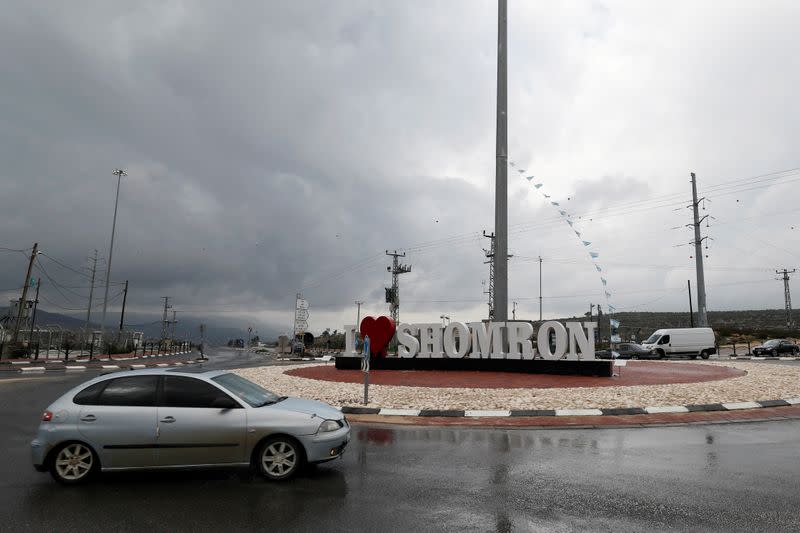 A car drivers past an Israeli road sign near Kfar Tapuach settlement in the Israeli-occupied West Bank