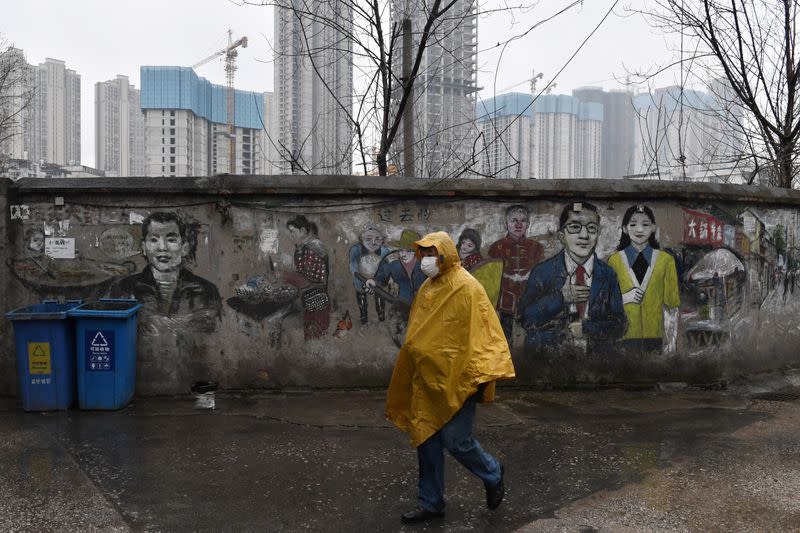 Un hombre con una mascarilla pasa por delante de un mural cerca de una obra en construcción en Wuhan, en la provincia de Hubei, China, el 28 de febrero de 2020