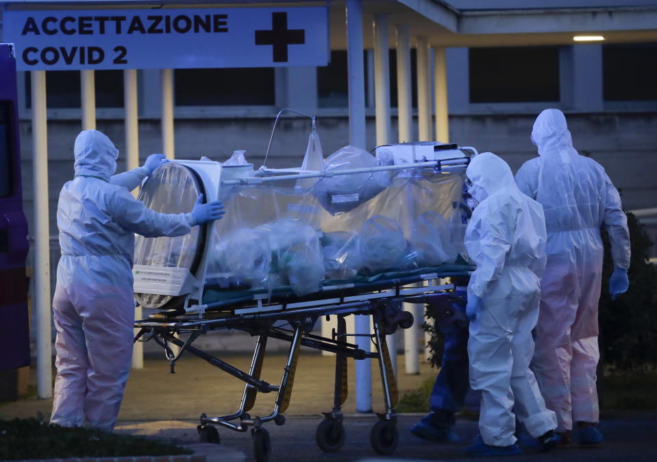 A patient in a biocontainment unit is carried on a stretcher at the Columbus Covid 2 Hospital in Rome, Monday, March 16, 2020. The new Columbus Covid 2 Hospital, an area fully dedicated to the COVID-19 cases at the Gemelli university polyclinic, opened today with 21 new ICU units and 32 new beds, in order to support the regional health authorities in trying to contain the pandemic. Sign at top in Italian reads "Admission COVID 19". For most people, the new coronavirus causes only mild or moderate symptoms. For some it can cause more severe illness, especially in older adults and people with existing health problems. (AP Photo/Alessandra Tarantino)