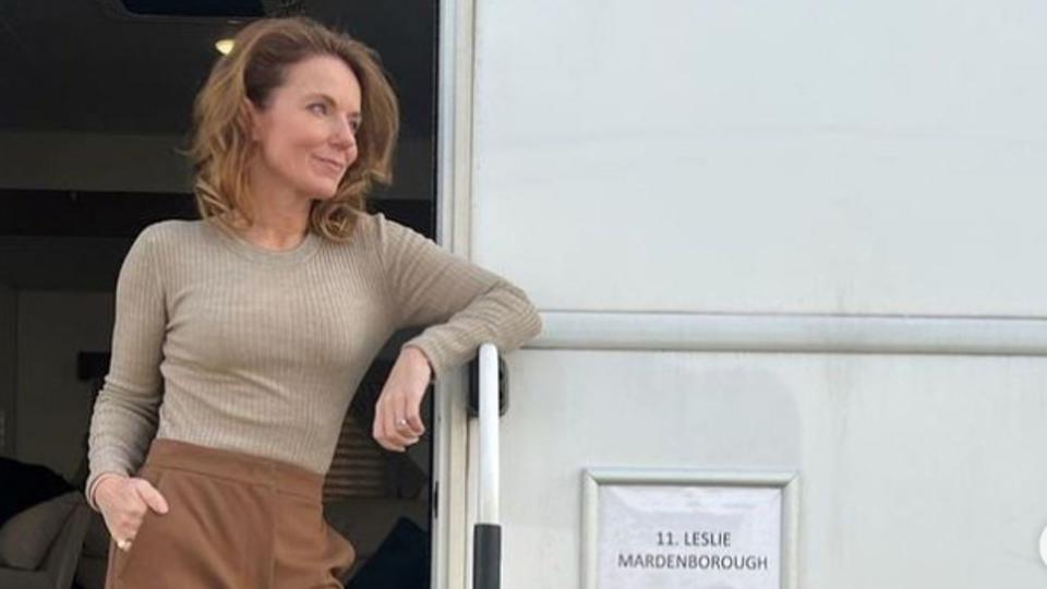 Geri Halliwell-Horner standing outside a film trailer in beige jumper and brown trousers