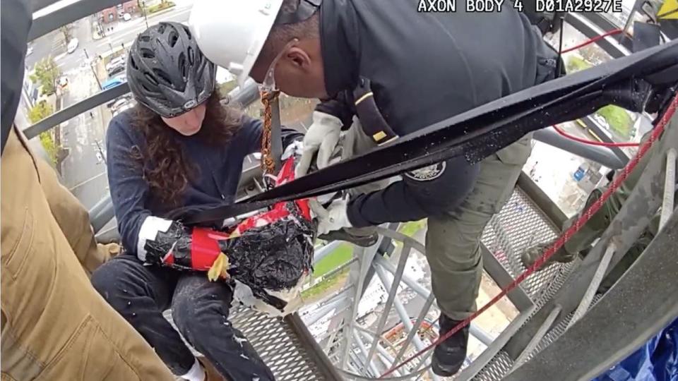 <div>APD Lt. Shedarren Fleming works to unchain a protester who climbed a construction crane to protest the new police training center. (APD)</div>