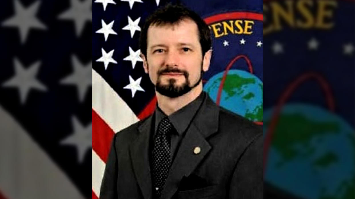 Sean Kirkpatrick, director of the All-domain Anomaly Resolution Office, with a U.S. flag and Defense Department flag behind him.