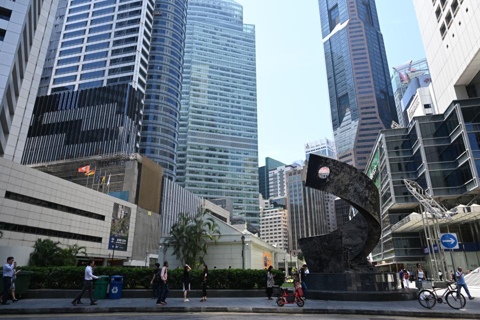 People walk past buildings in the financial business district of Raffles Place in Singapore. (Photo by ROSLAN RAHMAN/AFP via Getty Images)