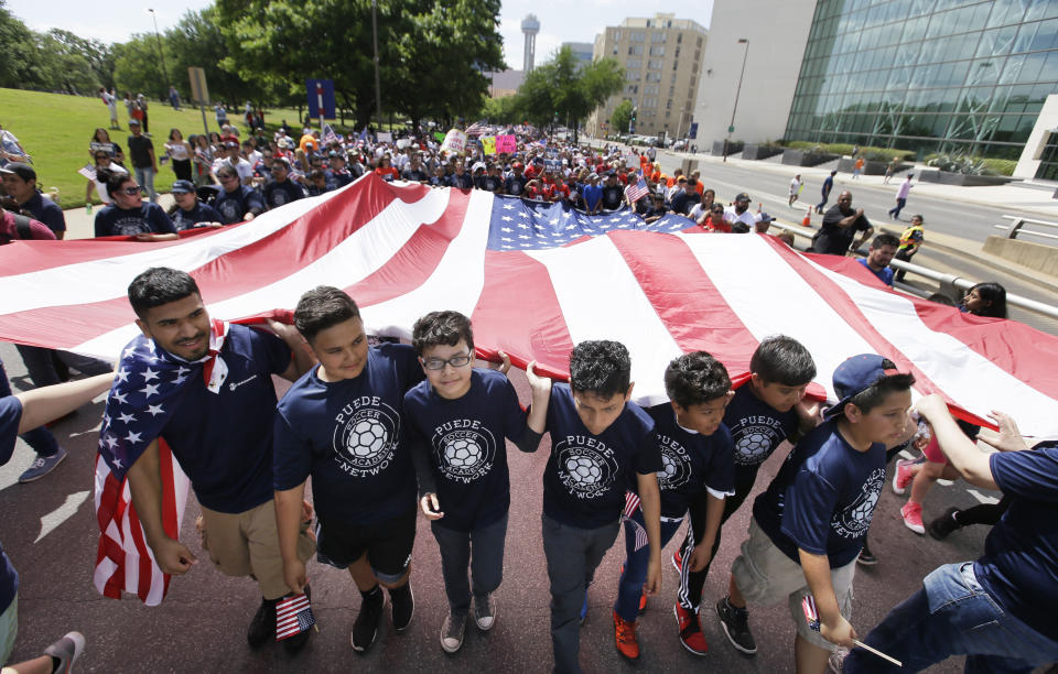 Youths and adults carry an American flag during a protest march through downtown Dallas, Sunday, April 9, 2017. Thousands of people are marching and rallying in downtown Dallas to call for an overhaul of the nation's immigration system and end to what organizers say is an aggressive deportation policy. (AP Photo/LM Otero)