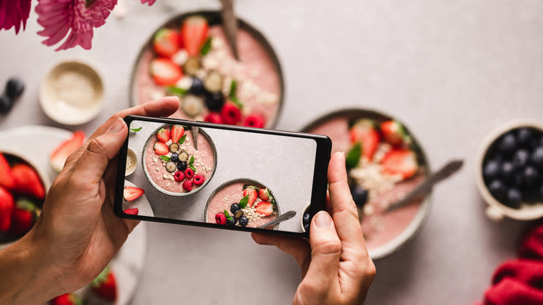 Person taking a photo of colorful smoothie bowls