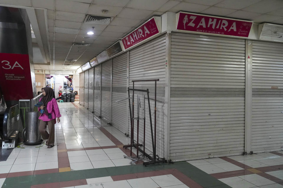 A person walks by closed and deserted shops in the Tanah Abang textile market in Jakarta, Indonesia, Thursday, Sept. 28, 2023. Chinese-owned app TikTok on Thursday said it regretted the Indonesian government's decision to ban e-commerce transactions on social media platforms, particularly the impact it would have on the millions of sellers who use TikTok Shop. (AP Photo/Tatan Syuflana)