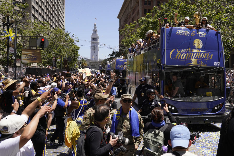 Stephen Curry and Damion Lee, right, ride atop a bus during the Golden State Warriors NBA championship parade in San Francisco, Monday, June 20, 2022. (AP Photo/Eric Risberg)