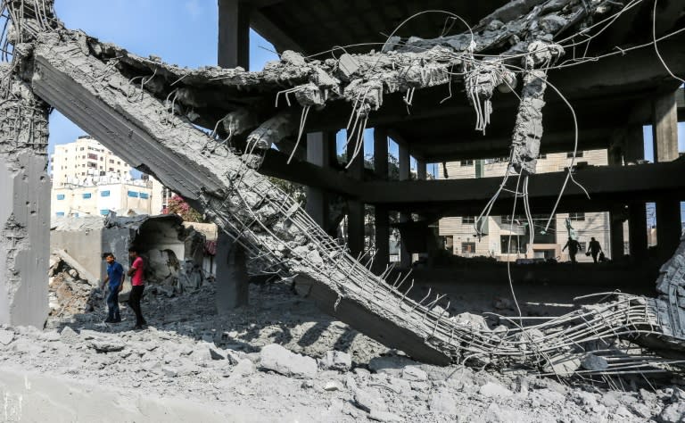 Palestinian youths walk through the wreckage of a building in Gaza City on July 15, 2018, the day after it was hit by Israeli air strikes