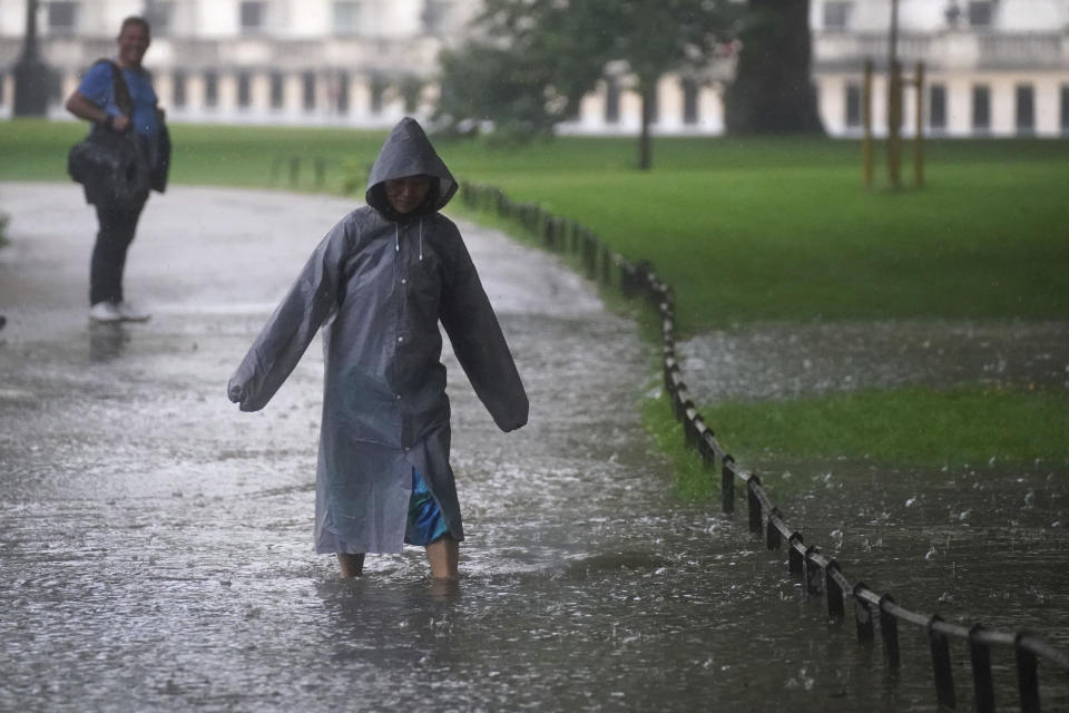 A woman walks through a flooded path in St James's Park in central London, Sunday July 25, 2021. Thunderstorms bringing lightning and torrential rain to the south are set to continue until Monday it is forecast. (Victoria Jones/PA via AP)