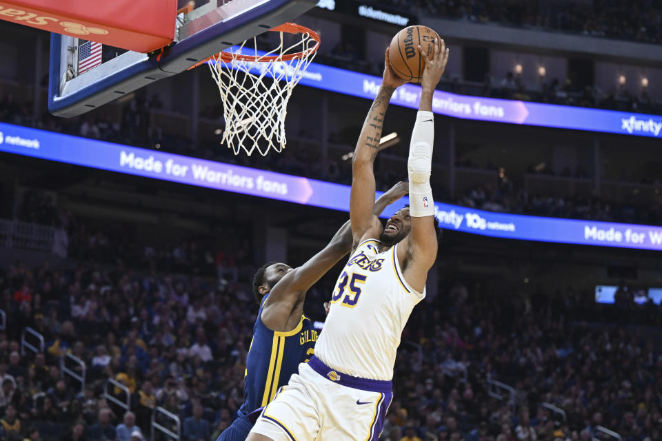 Los Angeles Lakers forward Christian Wood (35) dunks as Golden State Warriors forward Andrew Wiggins, left, attempts to block him during the first half of an NBA basketball game Saturday, Jan. 27, 2024, in San Francisco. (AP Photo/Nic Coury)