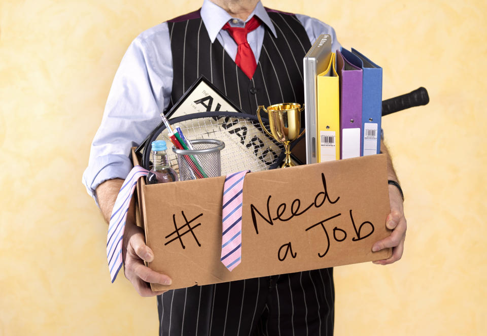 Laid-off person carrying a box that says "I need a job"