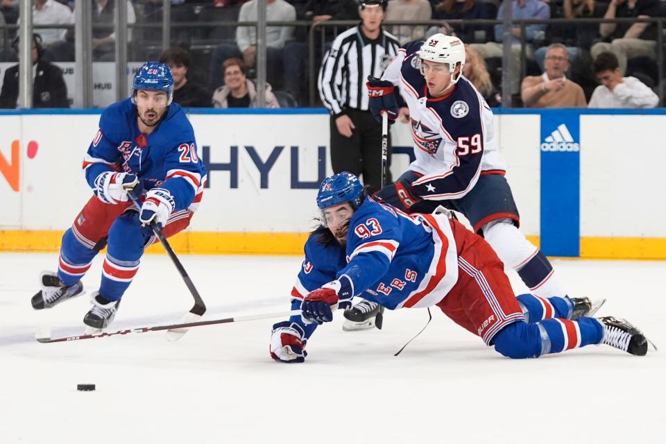 New York Rangers' Mika Zibanejad (93) and Chris Kreider (20) compete for control of the puck with Columbus Blue Jackets' Yegor Chinakhov (59) during the first period of an NHL hockey game Wednesday, Feb. 28, 2024, in New York.