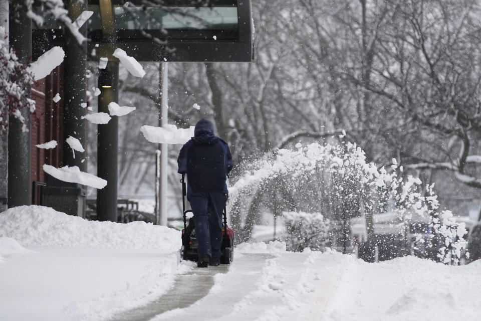 A man cleans a path from snow at front of a school in Wheeling, Ill., Friday, Jan. 12, 2024. (AP Photo/Nam Y. Huh)