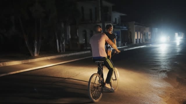 A a man pedals carrying a girl during a scheduled power outage in Bauta, Cuba.