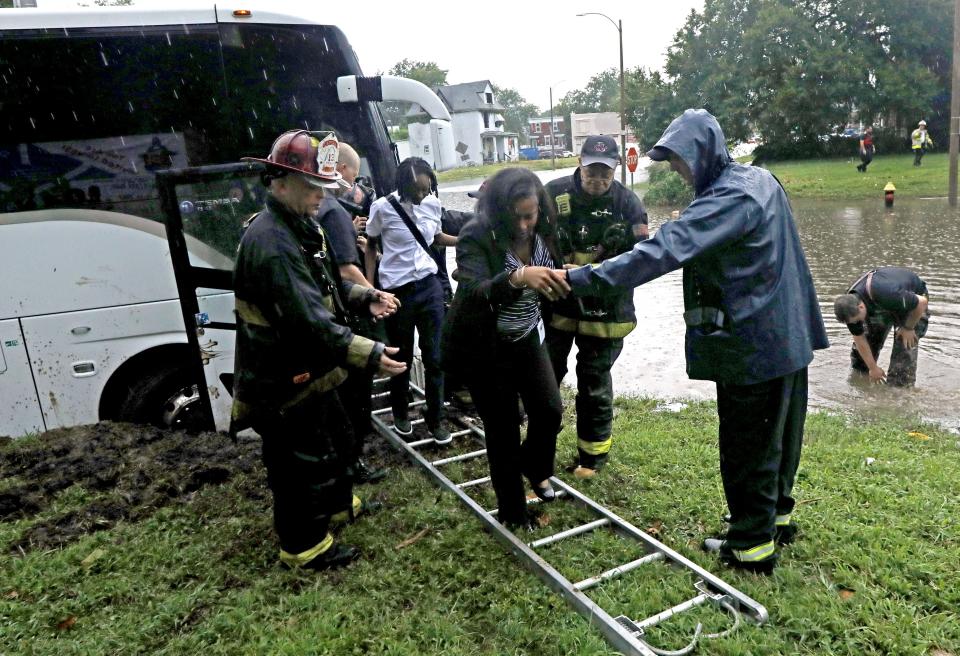 FILE - St. Louis Firefighters with Engine House No. 10 assist a group of adults and students off a bus that got stuck in rising flood waters on Thursday, July 28, 2022, at the intersection of Marcus and Page Avenues in St. Louis, Mo. The same stubborn weather system caused intense downpours in St. Louis and Appalachia that led to devastating and in some cases deadly flooding. (Laurie Skrivan/St. Louis Post-Dispatch via AP, File)