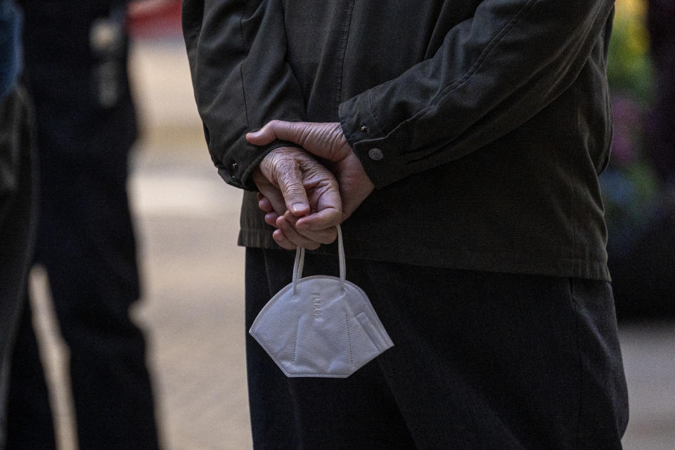 A customer holds a mask while waiting to enter a restaurant.