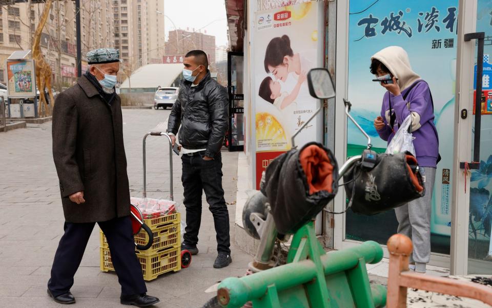 Residents wearing masks walk along the streets of Aksu in western China's Xinjiang region - Ng Han Guan /AP