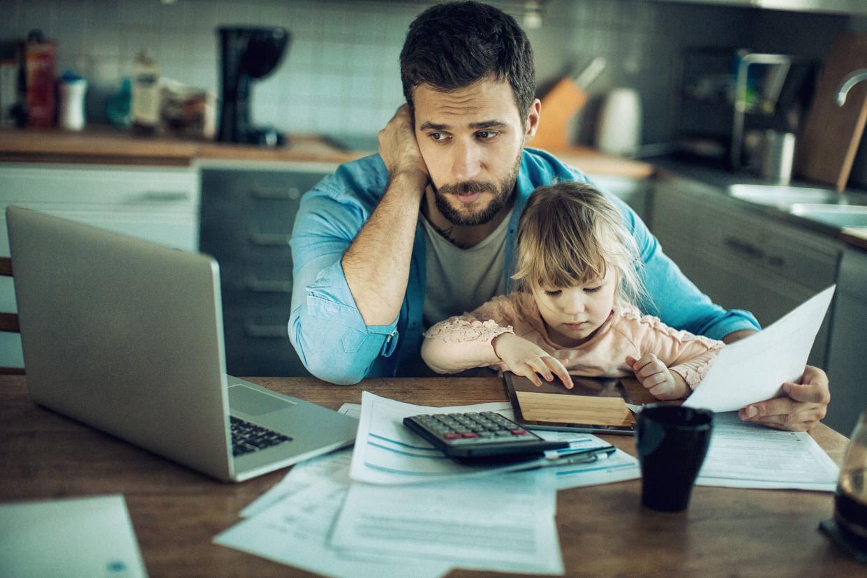 man at home with child doing finances on the kitchen table