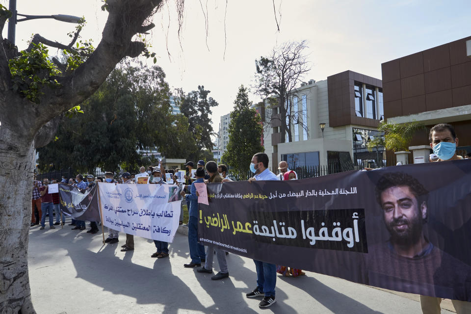 Supporters protest in front of the Casablanca Courthouse, in Casablanca, Morocco, Tuesday, Sept. 22, 2020, on the first day of the hearing of journalist and activist Omar Radi. The arrest of journalist Omar Radi follows numerous summons following a police investigation into suspicion of receiving funds linked to foreign intelligence. The investigation came after rights group Amnesty International accused Morocco of using Israeli-made spyware to snoop on its phone. Banner in Arabic reads: "Stop your lawsuits against Omar Radi". (AP Photo/Abdeljalil Bounhar)