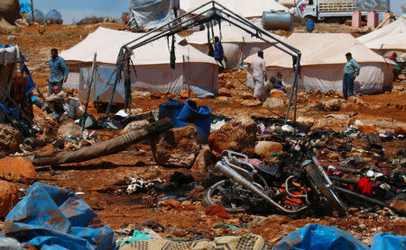 Men are pictured near the damage after air strikes on Thursday hit a camp for internally displaced people in Syria's Idlib province near the Turkish border, May 7, 2016. REUTERS/Ammar Abdullah