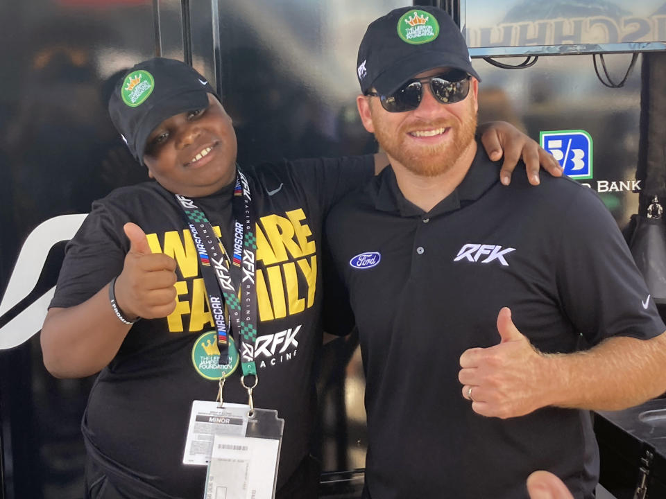 James Bromsey III, left, a sixth-grader at LeBron James' I Promise School in Akron, Ohio, poses with NASCAR driver Chris Buescher, Sunday, Aug. 7, 2022 in Brooklyn, Mich. Bromsey was given an all-access tour of Michigan International Speedway in Brooklyn, Mich., on Sunday. Chris Buescher’s No. 17 Ford had a paint job that highlighted the LeBron James Family Foundation. (AP Photo/Larry Lage)