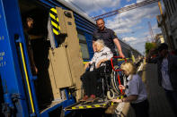 A woman fleeing from shelling boards an evacuation train at the train station in Pokrovsk, eastern Ukraine, eastern Ukraine, Friday, May 27, 2022. Volunteers have been racing to evacuate as many civilians as possible, particularly the elderly and those with mobility issues, as Russian forces make advances in the region. (AP Photo/Francisco Seco)